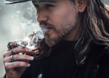 A man with a cowboy hat smoking, showcasing Western style and contemplation.